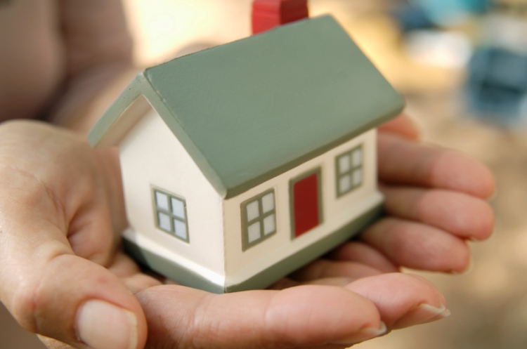 A person's hand holding a small toy house
