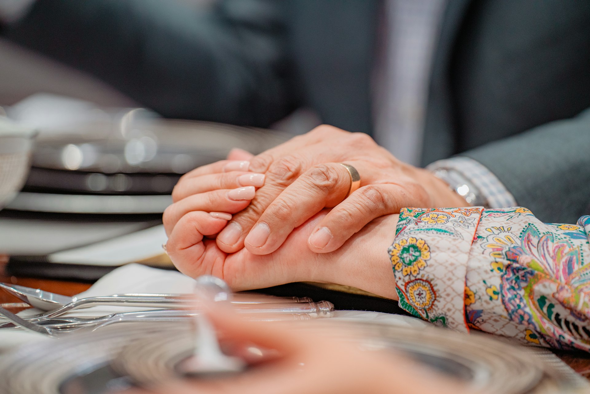 a close up of two people holding hands at a table